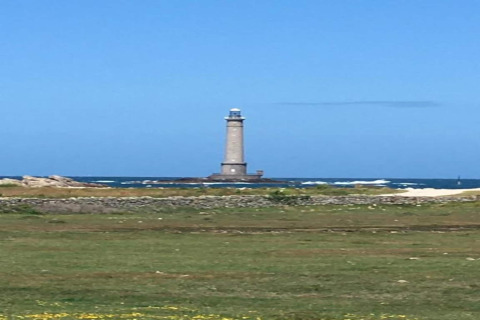 Vista de un alto faro junto al mar, tomada desde el césped cerca de 'Maison de vacances - LE PONCHEL' en Francia.