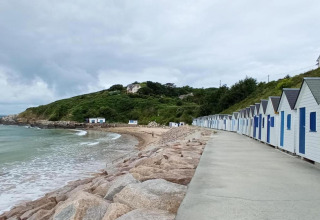 Casetas de playa junto al mar cerca de Maison de vacances - LE PONCHEL, Francia, con cielo nublado y colinas.