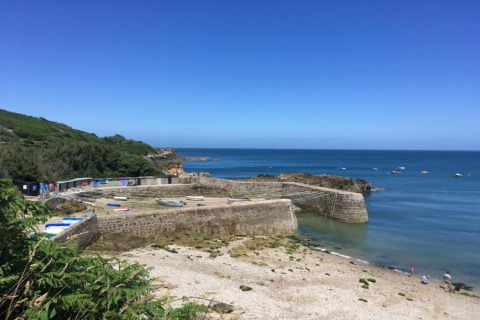 Stenkanthavn med bådehuse og både ved havet, under en klar blå himmel nær Maison de vacances - LE PONCHEL.