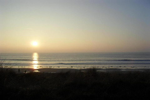 Atardecer sobre el mar visto desde Maison de vacances - LE PONCHEL, playa tranquila y luz dorada en Francia.