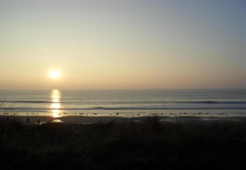 Sunset over the sea viewed from Maison de vacances - LE PONCHEL, calm beach with golden light in France.