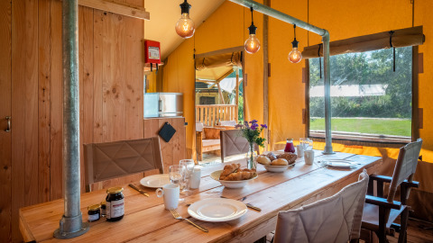 Intérieur de la Safari tent Comfort au Papillon Country Resort, Pays-Bas, avec table dressée pour le petit-déjeuner.