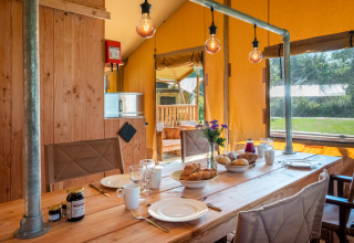 Intérieur de la Safari tent Comfort au Papillon Country Resort, Pays-Bas, avec table dressée pour le petit-déjeuner.