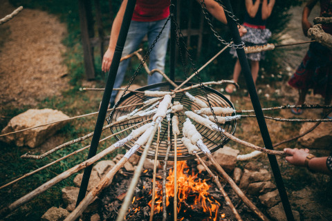 Children roast bread on sticks over a campfire at Campsite Junora, a holiday park in Nouvelle-Aquitaine, France.