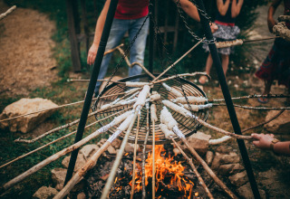 Children roast bread on sticks over a campfire at Campsite Junora, a holiday park in Nouvelle-Aquitaine, France.