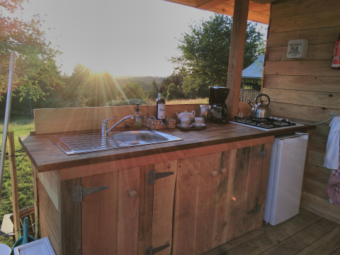 Rustic outdoor kitchen at Campsite Junora in Nouvelle-Aquitaine, France, with sunset and wooden decor.