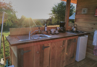 Rustic outdoor kitchen at Campsite Junora in Nouvelle-Aquitaine, France, with sunset and wooden decor.