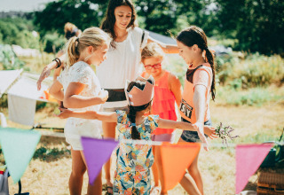 Children play outdoors at Campsite Junora in Nouvelle-Aquitaine, France, surrounded by colorful bunting flags.