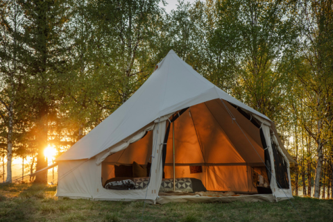 Large open tent at sunset in a wooded area at Campsite Junora, Nouvelle-Aquitaine, France, ideal for glamping.