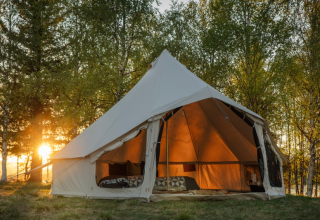 Large open tent at sunset in a wooded area at Campsite Junora, Nouvelle-Aquitaine, France, ideal for glamping.