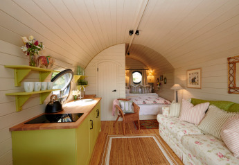 Intérieur douillet de la cabane The Campion au Royaume-Uni, avec cuisine, canapé et lit confortable.