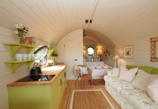 Cozy interior of The Campion pod in the UK featuring a kitchen, sofa, and bed with soft decor.