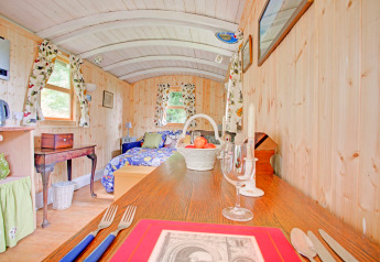 Vista interna della casa mobile 'Higher House' nel Regno Unito con pannelli in legno, letto, tavolo e finestre.