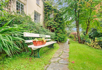 Panchina bianca e piante in vaso su sentiero di pietra presso Higher House, casa mobile nel Regno Unito.