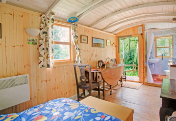 Interno della casa mobile Higher House nel Regno Unito, pannelli in legno, tende colorate e tavolo da pranzo.