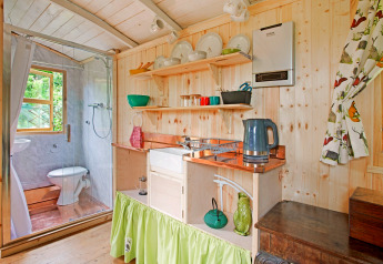 Cucina e bagno luminosi e compatti nella casa mobile 'Higher House' con rivestimenti in legno nel Regno Unito.