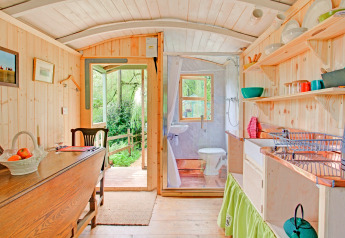 Interno luminoso della casa mobile Higher House nel Regno Unito, cucina in legno e vista sulla natura.