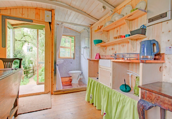 Interno luminoso della casa mobile Higher House nel Regno Unito, con pannelli in legno, cucina e bagno.