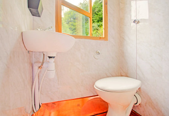 Bagno luminoso in una casa mobile con WC, piccolo lavandino e finestra affacciata sul verde nel Regno Unito.