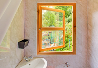 Bagno con finestra in legno aperta e vista giardino nella casa mobile 'Higher House' nel Regno Unito.