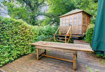 Area esterna della casa mobile Higher House nel Regno Unito con tavolo di legno e piccolo capanno.