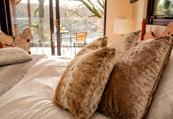 Cozy bedroom with plush pillows and balcony view at Yeworthy Eco-Treehouse in the United Kingdom.