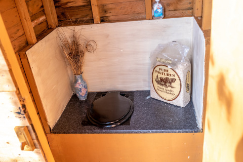 Toilette compostante presso Yeworthy Eco-Treehouse, Regno Unito, con trucioli, igienizzante e fiori secchi.