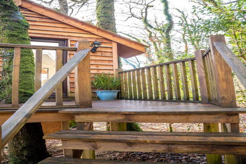 Scala e terrazza in legno che portano a una casa sull’albero a Yeworthy Eco-Treehouse, Regno Unito.