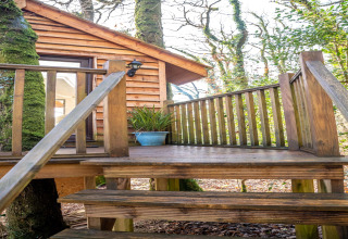 Scala e terrazza in legno che portano a una casa sull’albero a Yeworthy Eco-Treehouse, Regno Unito.