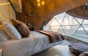 Knole Luxury Dome slaapkamer met luxe bed, grote ramen en prachtig uitzicht op de natuur in het VK.