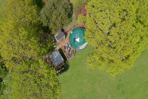 Aerial view of Knole Luxury Dome in the UK, surrounded by trees, lawn, and an outdoor seating area.