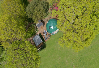 Aerial view of Knole Luxury Dome in the UK, surrounded by trees, lawn, and an outdoor seating area.