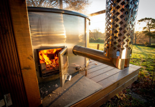 Wood-fired outdoor stove at Knole Luxury Dome, UK, with flames burning and scenic countryside behind.