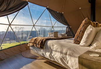 Knus interieur van Knole Luxury Dome in het Verenigd Koninkrijk met comfortabel bed en panoramisch uitzicht.