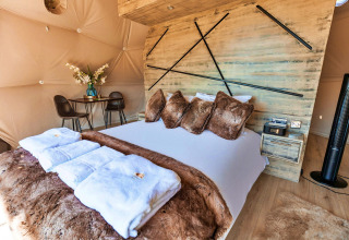 Bedroom inside Scotney Luxury Dome, UK, featuring plush decor, faux fur bedding, and modern accents.