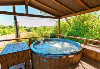 Bubbelbad buiten onder een houten dak met uitzicht op velden bij Scotney Luxury Dome in het Verenigd Koninkrijk.