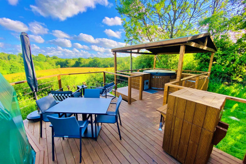 Outdoor deck at Scotney Luxury Dome in the UK, featuring dining area, hot tub, and scenic countryside views.