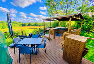 Outdoor deck at Scotney Luxury Dome in the UK, featuring dining area, hot tub, and scenic countryside views.