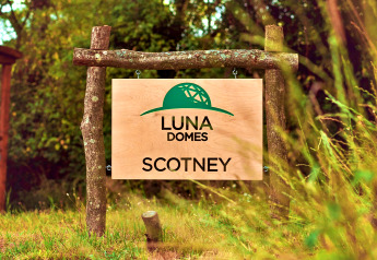 Houten bord met 'LUNA DOMES SCOTNEY' en groen koepellogo in het groen van het Verenigd Koninkrijk.