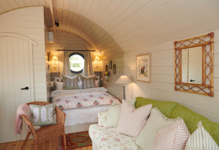 Cozy bedroom in The Campion pod, UK, featuring soft lighting, floral bedding, and charming cottage decor.