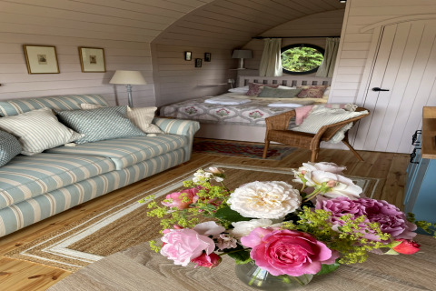 Intérieur chaleureux du pod The Cornflower avec canapé rayé, fleurs fraîches et lit douillet au Royaume-Uni.