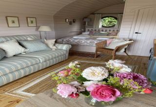 Gezellige inrichting van The Cornflower pod met gestreepte bank, bloemen en comfortabel bed in het VK.