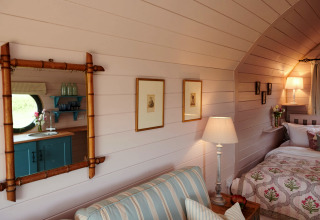 Intérieur chaleureux du pod «The Cornflower» au Royaume-Uni avec lit, canapé rayé et lampes.