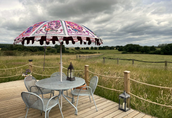 Terrasse en bois avec table et parasol coloré sur The Cornflower pod, dans la campagne britannique.