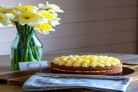 Taart met gele topping en narcissen in vaas op houten tafel bij The Cornflower pod in het Verenigd Koninkrijk.