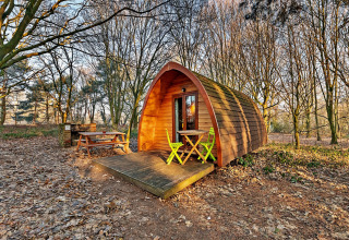 Gezellige houten pod met veranda en stoelen in een bos bij Eadmund Pod, Verenigd Koninkrijk.