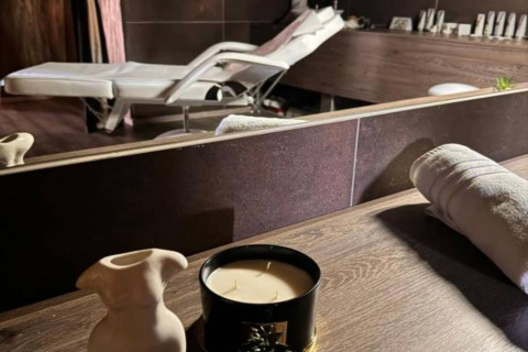 Salle de spa dans un chalet, avec table de soins, bougie, serviette roulée et objets de décoration.