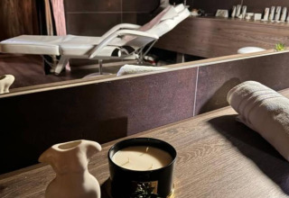 Salle de spa dans un chalet, avec table de soins, bougie, serviette roulée et objets de décoration.