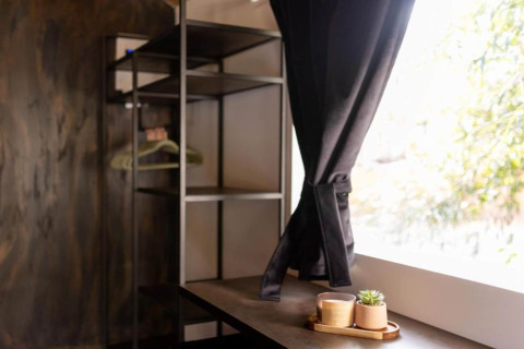 Intérieur de chalet chaleureux avec étagères ouvertes, rideaux noirs et plateau avec tasses et plante.