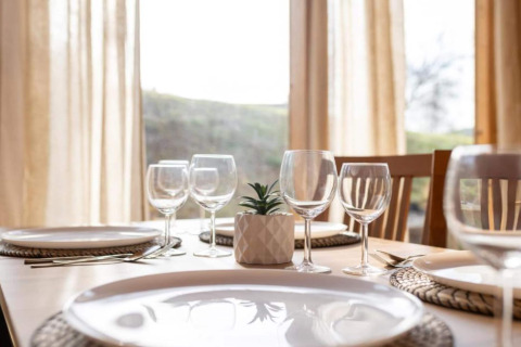Table dressée dans un chalet, verres à vin, assiettes et une petite plante ornent le centre de la table.